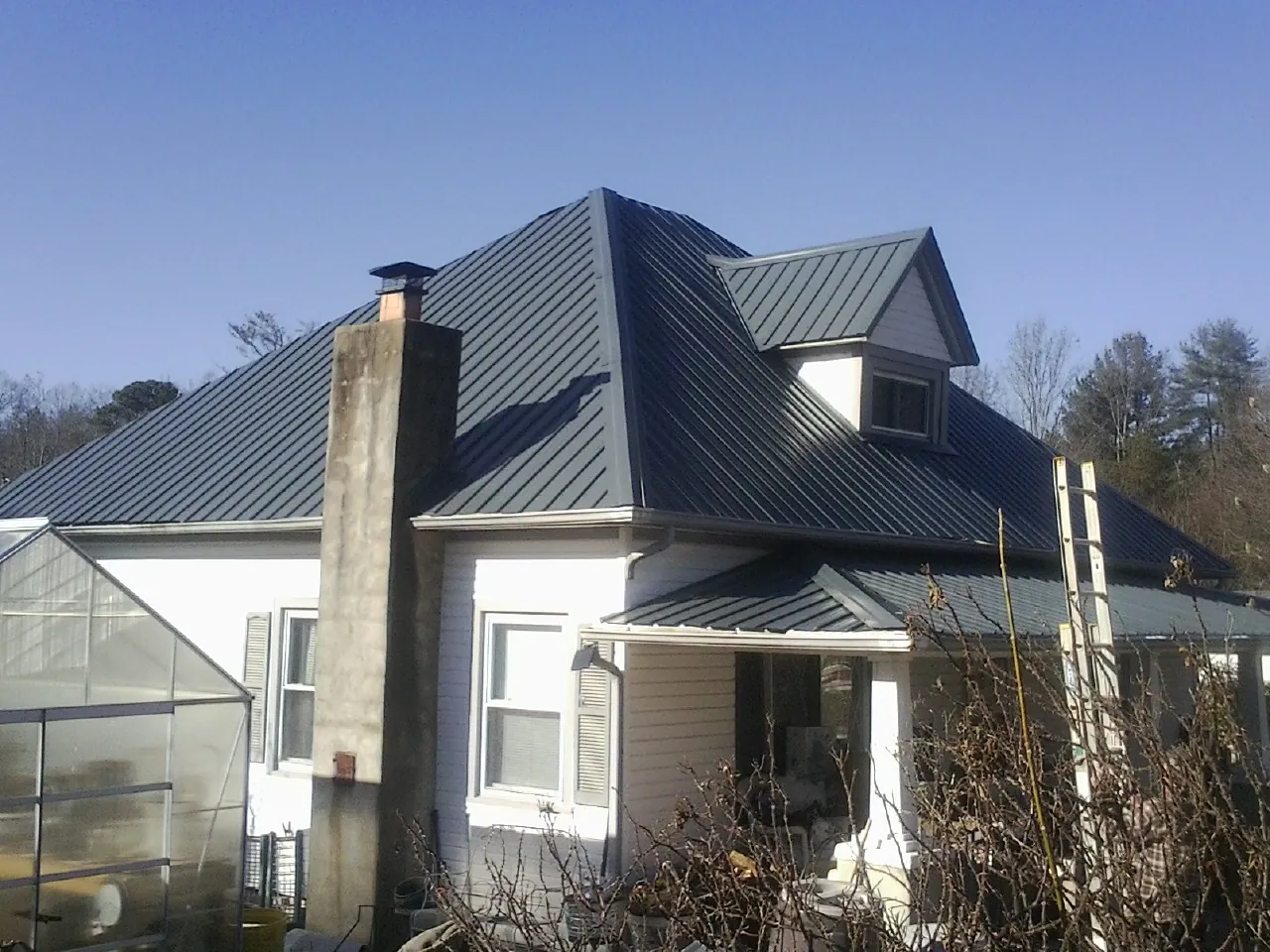Dark blue standing seam metal roof on a white farmhouse with dormer — Slate & Tile Roof Repair by Roofing Brothers in Fountain Run