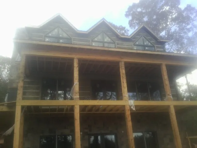 Dormers and porch framing on a large log home under construction — Roof Coating work by our crew in Fountain Run