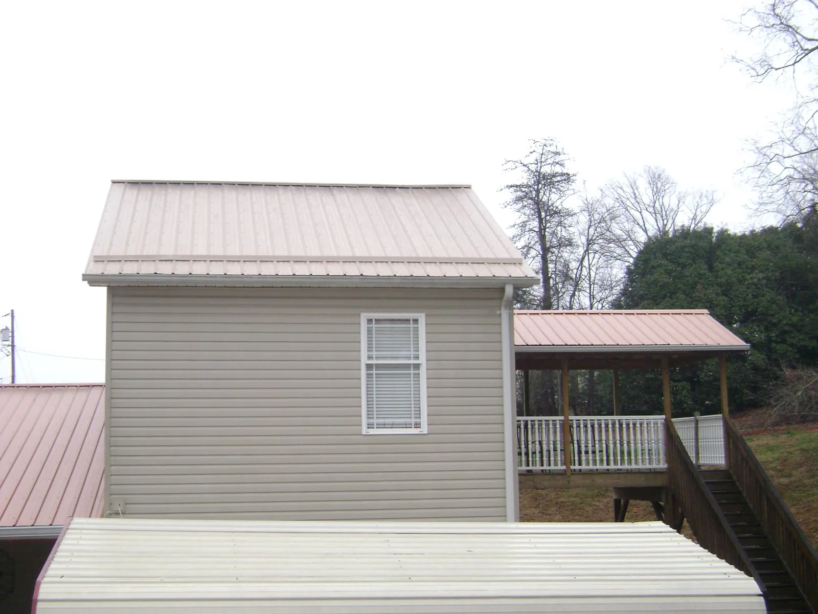 Tan metal roofs on a two story addition and attached porch, from a Roof Replacement job in Fountain Run