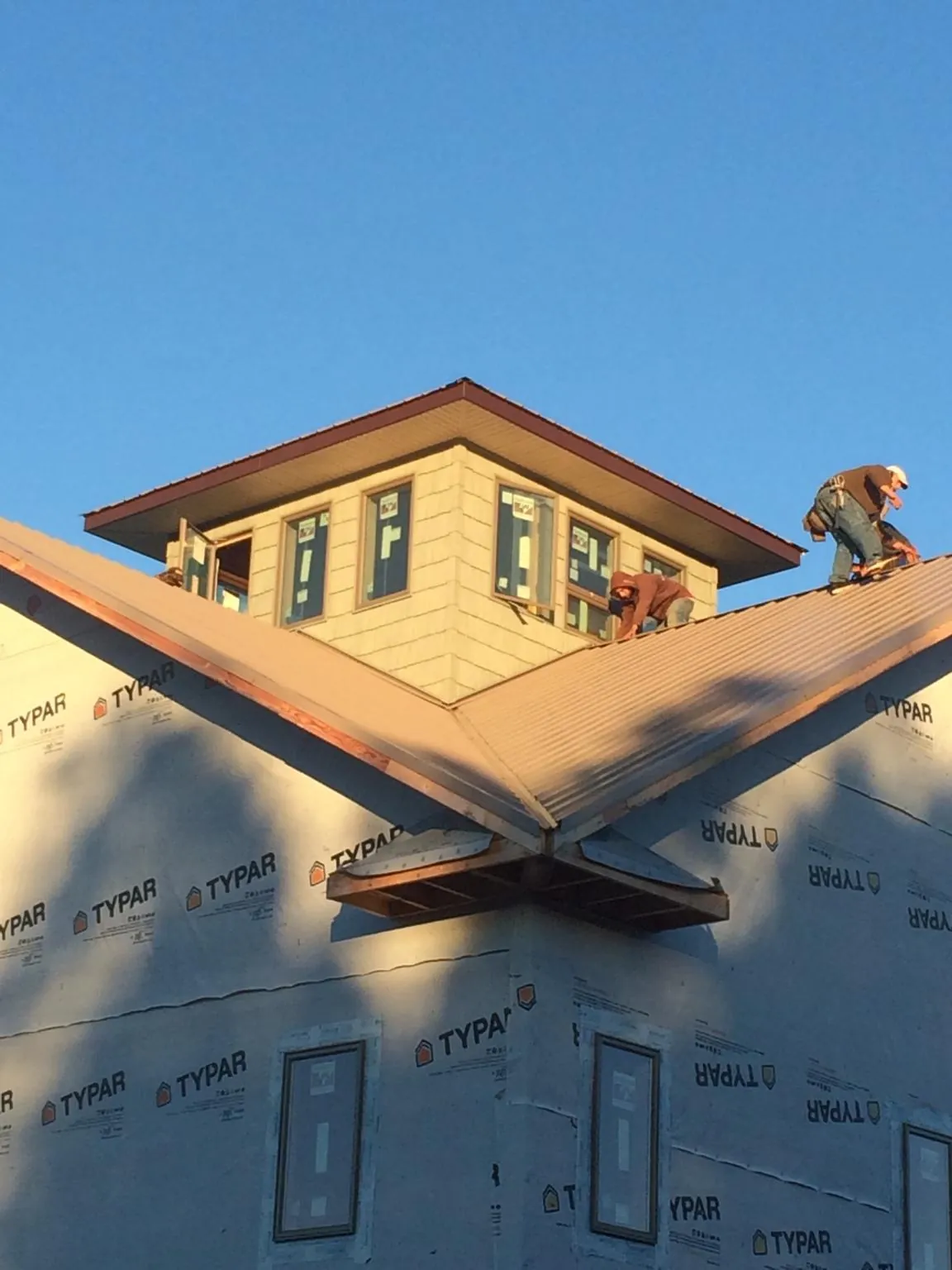 Roofers working around a rooftop cupola on a new metal roof at sunset — Roof Waterproofing in Fountain Run by Roofing Brothers